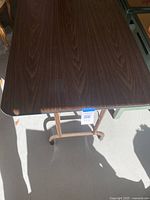 Top view of the 4x2 foot folding table showing dark wood grain laminate surface with minor wear.