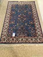 Full view of the 6x4 decorative oriental rug laid on carpet floor showing overall pattern and fringed edges.