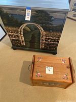 Small chest dresser with detailed hand painted outdoor archway scene and flowers, and adjacent smaller decorative wooden stool with floral painting.