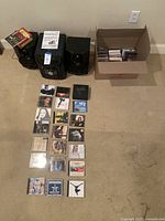 Photo showing stereo system main unit, two speakers, box of CDs, and CDs laid out on the ground.