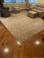 Full view of the beige and blue traditional floral patterned rug placed on a hardwood floor in a living room.
