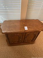 Photo showing the top and front of the wooden buffet with the slide-out top closed, highlighting the wood grain and cabinet door details.