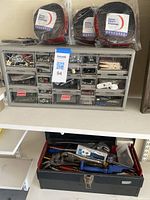 Shelving unit with organized small hardware and toolbox beneath, context photo not directly related to the lot items.