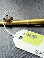 Ring resting on gold pen, string tag visible