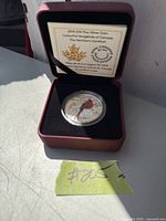Photo of 2015 $20 color fine silver coin featuring a red songbird, presented in a burgundy presentation box with informational card from Royal Canadian Mint visible