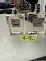 Two clear rectangular glass bottles of Chanel No. 5 L'Eau perfume, both full, one missing spray tip