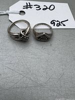 Two silver ladies rings stamped 925 on a tag marker showing lot number and metal purity.