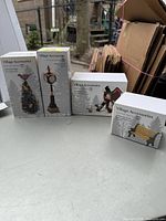 Four boxed Dept. 56 Village Accessories including tree with bird, street clock, birdhouse, and park bench