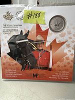 Closed packaging showing the coin mounted on a card featuring an RCMP officer and horse with a red maple leaf background.