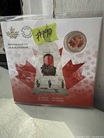 Photo of $5 fine silver Remembrance Day coin encased in a souvenir card featuring the Canadian War Memorial and maple leaf design.