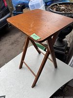 Side angled view of vintage wood folding side table showing table top and folding legs