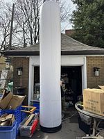 Full view of tall white inflatable advertising tube set up outdoors showing overall height and diameter