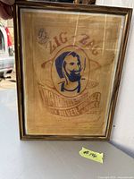 Photo showing framed vintage Zig-Zag advertising print with an image of a man with a cap and pipe, text details visible.