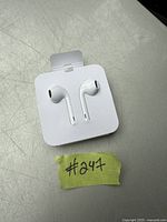 Photo of white Apple EarPods in original packaging, showing the earbuds mounted on a white cardboard backing.