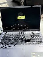 Open ASUS laptop with power adapter placed on keyboard, showing locked sign-in screen.