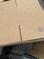 Stack of flattened cardboard boxes showing the texture and corrugation of the material with Uline brand stamp visible.