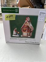 Front view of the boxed Dept. 56 Christmas Market The Gingerbread Booth showing product image, title, and series line.