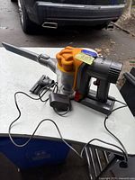 Dyson portable vacuum on table with charger and nozzle attachment visible