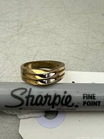 Ring placed beside a Sharpie fine point marker on a gray surface