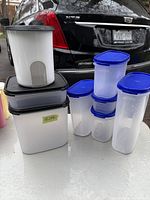 Photo of multiple new Tupperware storage containers with blue lids and various shapes and sizes.
