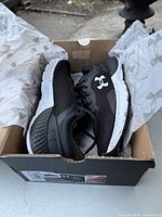 Pair of new black Under Armour Charged Escape running shoes in box with branded tissue paper