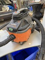 Full side and top view of the RIDGID portable vacuum showing hose attached, power cord wound, and wheels.