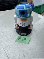 Front view of the R2-D2 Funko Pop figure on black Star Wars base with Pride design and sticker #60 placed on table.