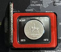 Close-up of the 1973 Canadian silver dollar coin in protective case showing front with RCMP mounted policeman.