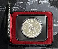 Close-up of the 1975 Canadian Silver Dollar coin in black and red protective case showing front design of horseback rider and Calgary skyline.