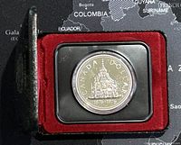 1976 Canadian silver dollar coin in a black protective case with red velvet interior showing the Parliament building design and date markings.