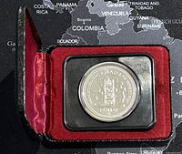 Photo of the silver coin inside red velvet-lined black case with lid open.