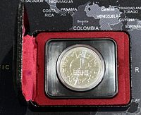 Photo of the silver coin in its presentation case with red velvet interior, showing front side details.