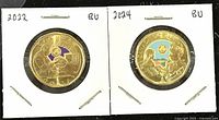 Front and back of 2022 and 2024 coloured Canadian Loonies coins in holders, showing the coin surface and design details