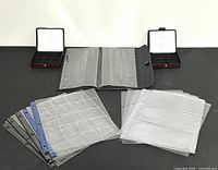 Wide view of all banknote and coin holders, plastic sheets, and cases arranged on a table.