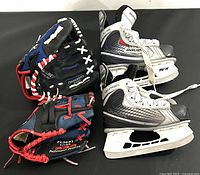 Image showing one pair of youth hockey skates size 10Y and two baseball gloves lying side by side against black background.