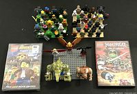Photo showing two LEGO DVDs in original cases and three LEGO character builds on baseplates including a winged figure and two animal figures