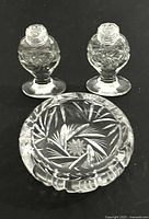Image showing the vintage footed crystal salt and pepper shakers with the pinwheel candy dish together on a dark surface.