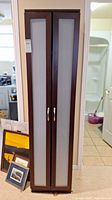 Front view of the tall storage cabinet showing two frosted glass paneled doors with silver handles and a dark brown frame.