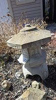 Full view of the cement garden pagoda showing the tiered roof and carved features.