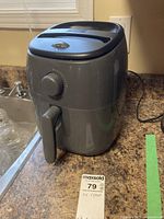 Gray Dash air fryer shown from front on kitchen counter, with power cord visible.