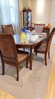 Photo showing the dining table and three chairs from an angle, including table surface with decorative items and the upholstery on chairs.