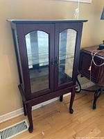 Front view of dark wood display cabinet with glass doors and arched glass panels.