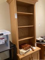 Full view of oak wood display hutch with three open shelves and items on the second shelf.