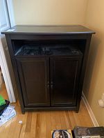 Front view of dark wood cabinet with closed doors showing some wear and scuffs on surface.