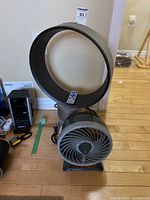 Photo showing Dyson bladeless fan with circular design and remote control inside the ring, also showing the Duracraft table fan in front