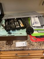 Multiple metal skewers stacked together with assorted cutting boards and black zip ties on kitchen counter.