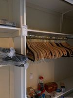 Wooden and felt-covered clothes hangers on a wooden rack in a closet, showing mostly natural wood hangers with metal hooks.