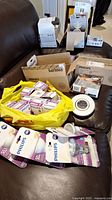 Lot showing multiple Philips light bulb boxes and packs, some in a yellow plastic bag with others spread on a black leather couch.