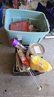 Large turquoise plastic storage tub with hand tools, painting supplies, roller, and other assorted items