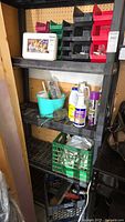 Shelf with plastic organizers holding small hardware and hand tools, white Rexall first aid kit box on top shelf, plastic bucket with bottles and adhesives, green plastic milk crate with tools.